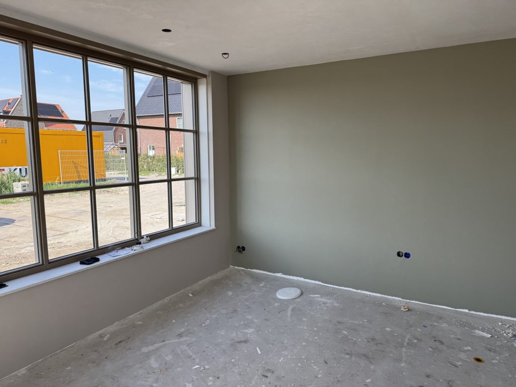 Nieuwbouwkamer waarvan een wand in een grijsgroene kleur is gesausd
